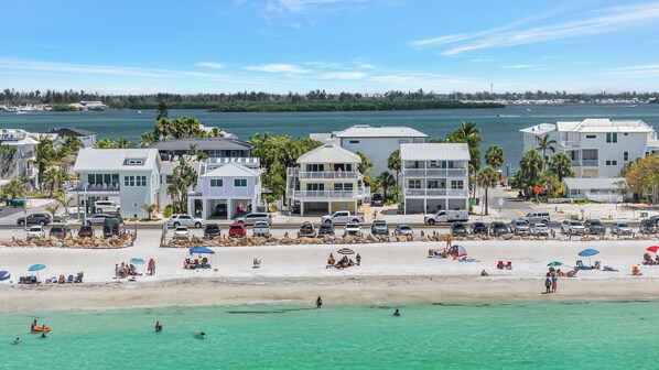Um imóvel à beira-mar com edifícios de vários andares, uma praia arenosa e águas turquesa cristalinas.