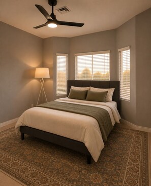A bedroom with a bed, a standing lamp, a ceiling fan, and a window with blinds. - Desert Disconnect | Pool • Putting Green (Gilbert)