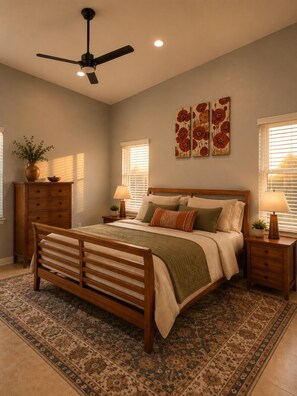 A bedroom with a bed, nightstands, a ceiling fan, a window with blinds, and a decorative wall piece. - Desert Disconnect | Pool • Putting Green (Gilbert)