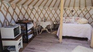 A tent with a bed, a small table, and a shelf with a microwave. - 1 Bed in Bronington (oc-g39074) (Bronington)