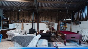 Une pièce au décor rustique, avec une table de billard, des meubles en bois, une bibliothèque et une cheminée.