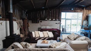Un intérieur rustique avec une cheminée, des murs en bois et un coin salon confortable agrémenté d’un échiquier.