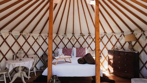 L'intérieur d'une yourte, avec un lit, une table et une commode.