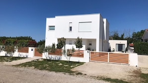 A modern two-story house with a flat roof, a small front porch, and a fenced yard. - Comfortable Family Retreat With Pool (Vodnjan)