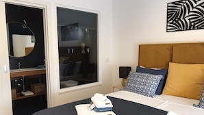 A hotel room with a bed, a bedside table, a nightstand, a window, and a bathroom visible through the door. - Comfortable Family Retreat With Pool (Vodnjan)