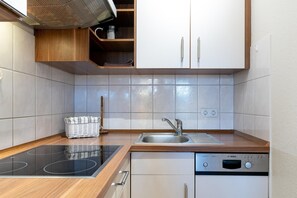 A modern kitchen with a built-in stove, sink, and dishwasher. - Ostseeurlaub - Strandnahe Ferienwohnung mit Balkon in Sellin (Sellin)