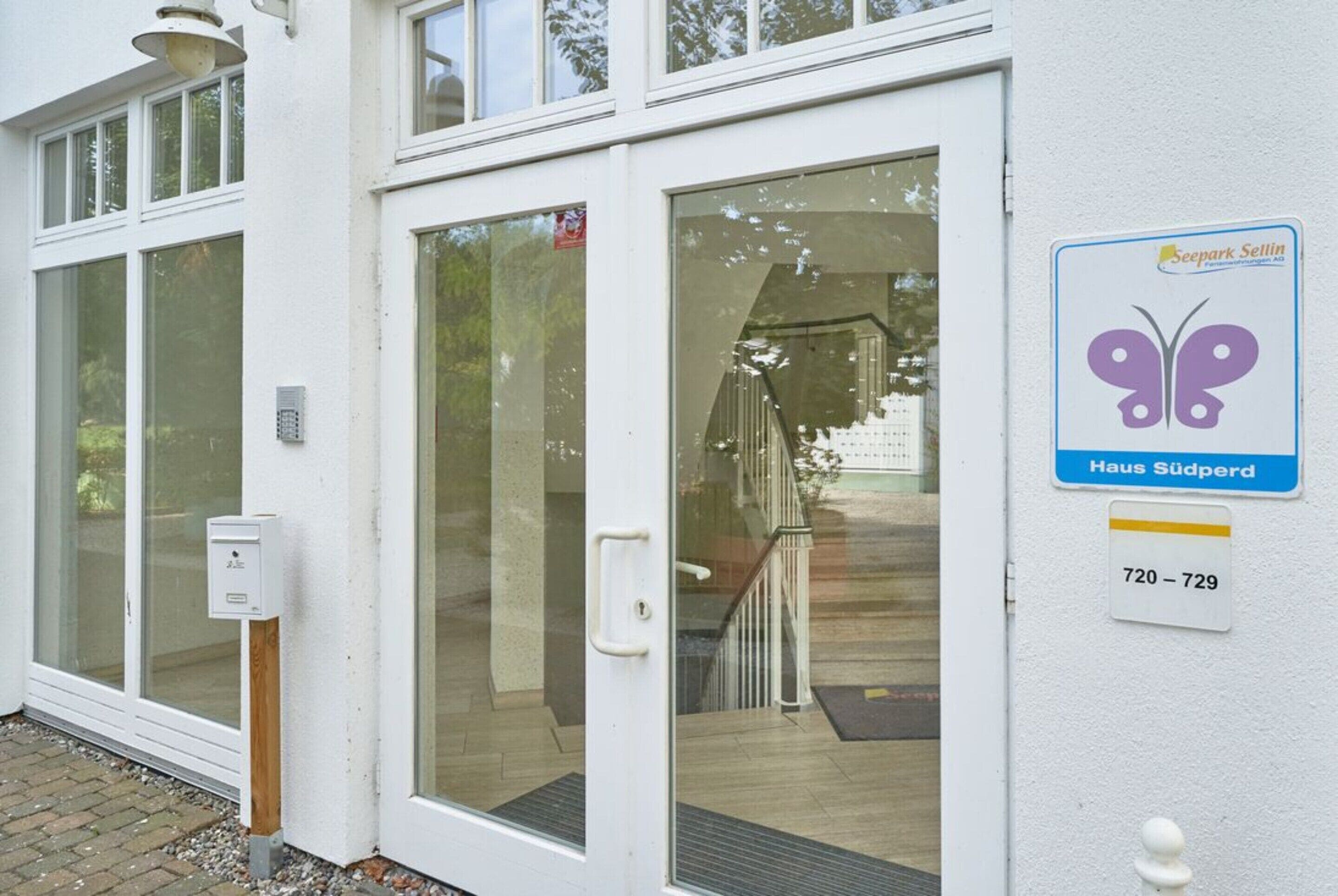 A white building with a glass door, a butterfly logo sign, and a number sign.