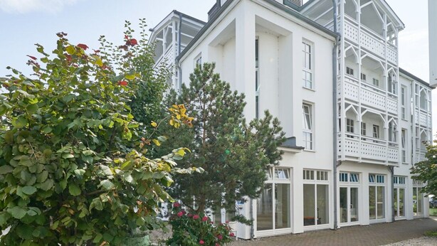 A white building with multiple windows and balconies, surrounded by trees and shrubs. - Komfortable Ferienwohnung fur bis zu 4 Personen (Sellin)