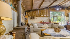 A rustic interior with a wooden stove, a sofa, and a dining table. - 1 Bed in Bronington (oc-d39075) (Bronington)