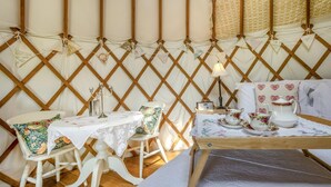 A cozy room with a wooden lattice wall, a table set with tea service, and a chair with a floral cushion. - 1 Bed in Bronington (oc-d39075) (Bronington)