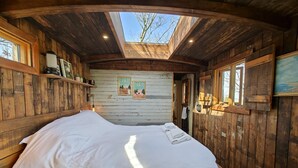 Une pièce en bois avec un lit, une lucarne et des murs en bois.