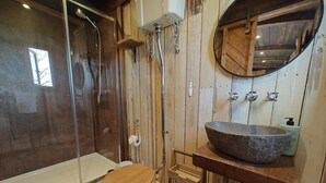 Une salle de bain avec un meuble-lavabo en bois, un grand lavabo, des toilettes et une douche à parois de verre.