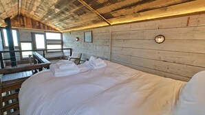 A wooden cabin-style room with a bed, two chairs, a small table, and a window. - 1 Bed in Earsdon (oc-l40253) (Earsdon)