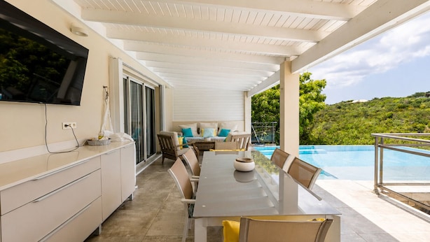 A covered outdoor area with a pool, a dining table, and a sofa.