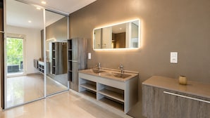 A modern bathroom with a large mirror, a double sink, and a cabinet.