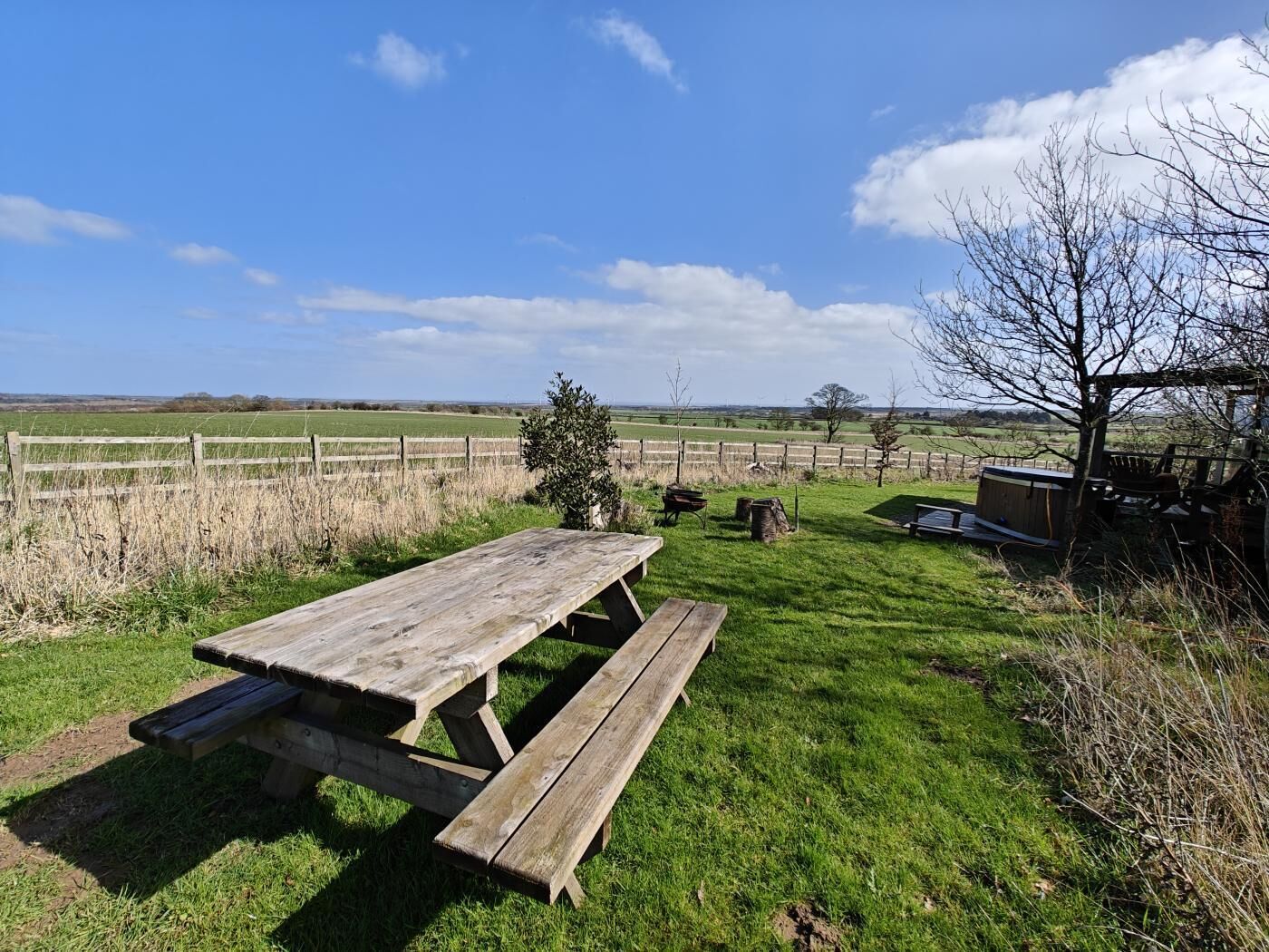 Een picknicktafel in een grasveld met een hek op de achtergrond.