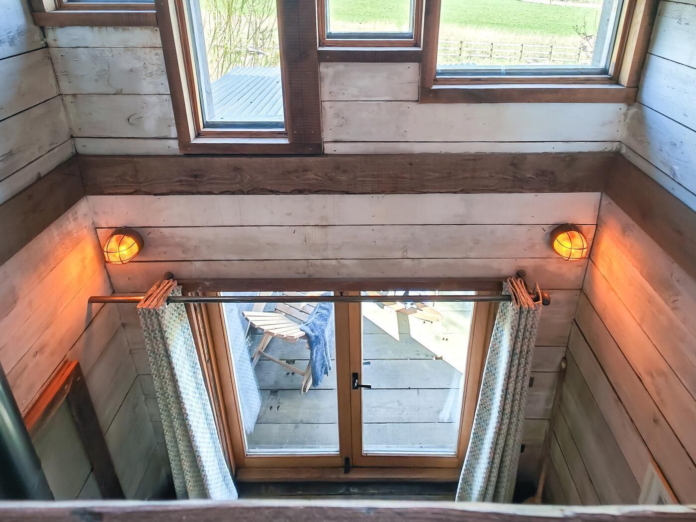 A wooden interior with a view of the outside through a door.