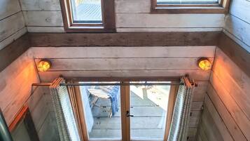 A wooden interior with a view of the outside through a door.