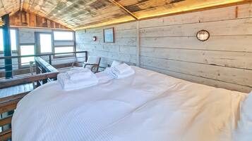 A wooden cabin-style room with a bed, a chair, and a window.