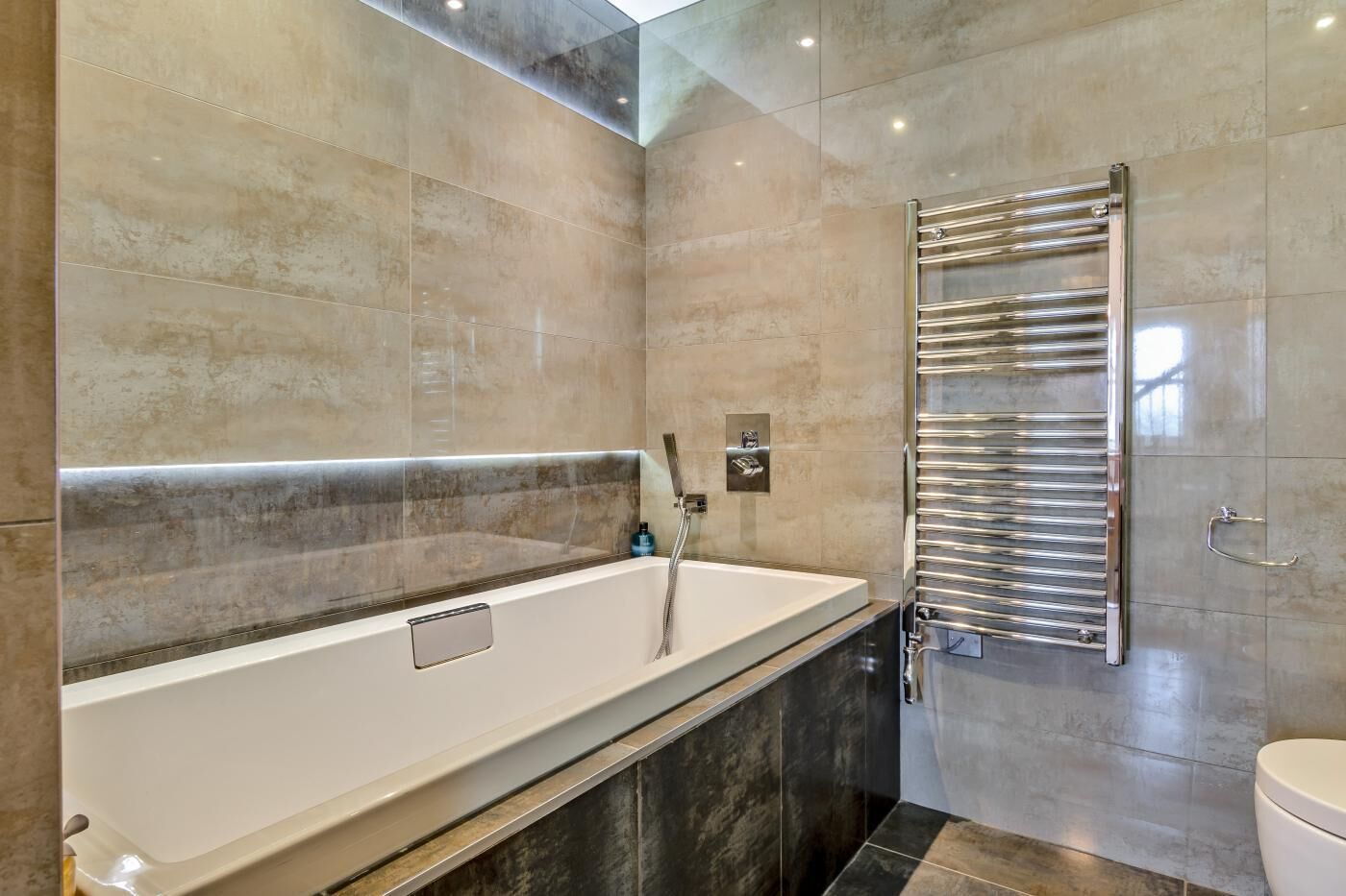 A modern bathroom with a large bathtub, a glass-enclosed shower, and a toilet.