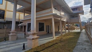 A two-story building with a covered patio area, columns, and a flat roof.