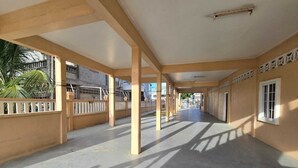 A covered corridor with columns, a concrete floor, and a view of buildings outside.