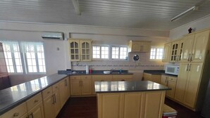 A kitchen with wooden cabinets, a central island, a microwave, and a red cooler.