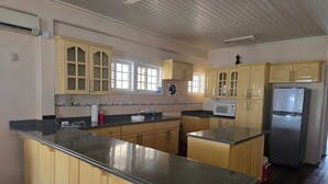 A kitchen with wooden cabinets, a granite countertop, a microwave, and a refrigerator.