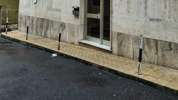 Ein Gebäude mit Betonfassade, einem kleinen Fenster mit Pflanze und einer Tür mit der Nummer 2.