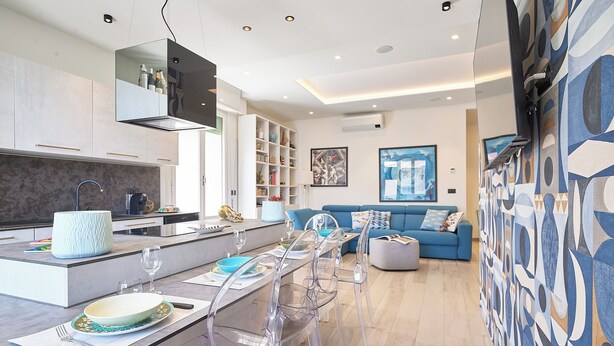 Una cucina moderna con zona pranzo, divano e parete decorata.