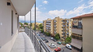 Un balcone con vista su una zona residenziale, con edifici a più piani e auto parcheggiate.