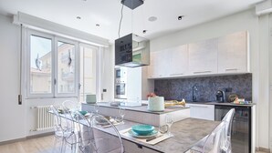 Una cucina moderna con un tavolo da pranzo in vetro, sedie trasparenti e forno a incasso.