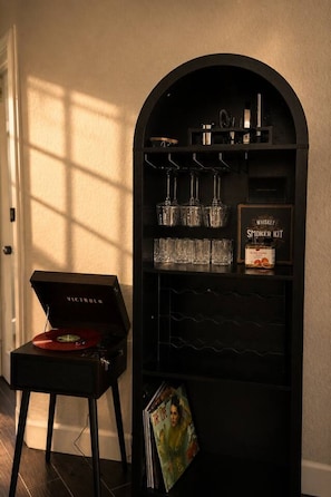 Eine schwarze, gebogene Vitrine mit einer Whiskey-Ausrüstung, Gläsern und einem Plattenspieler.