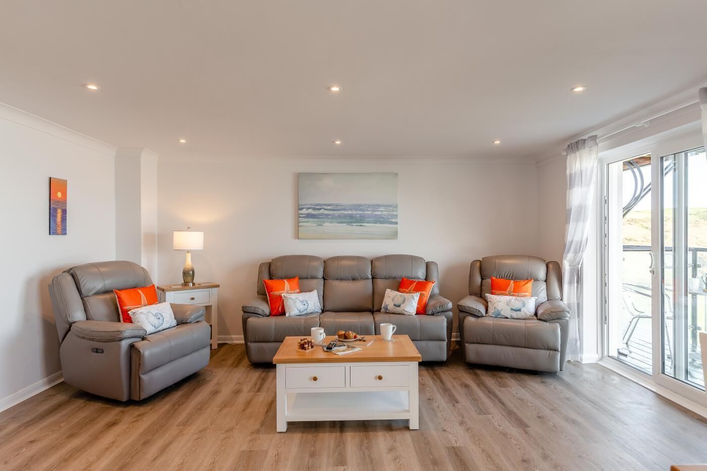 A living room with three leather sofas, a coffee table, and a painting on the wall.