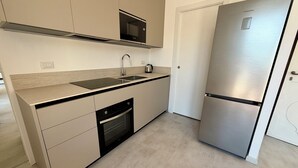 Et moderne køkken med et rustfrit stål køleskab, en Bosch opvaskemaskine, en mikrobølgeovn og en vask.