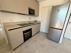 Eine moderne Küche mit einem Edelstahl-Kühlschrank, einem Geschirrspüler von Bosch, einer Mikrowelle und einem Spülbecken.