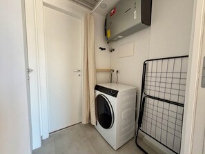 A laundry room with a washing machine, a drying rack, and a utility meter on the wall. - Peonie 5 - Two Bedroom Apartment, Sleeps 5 (Rapallo)