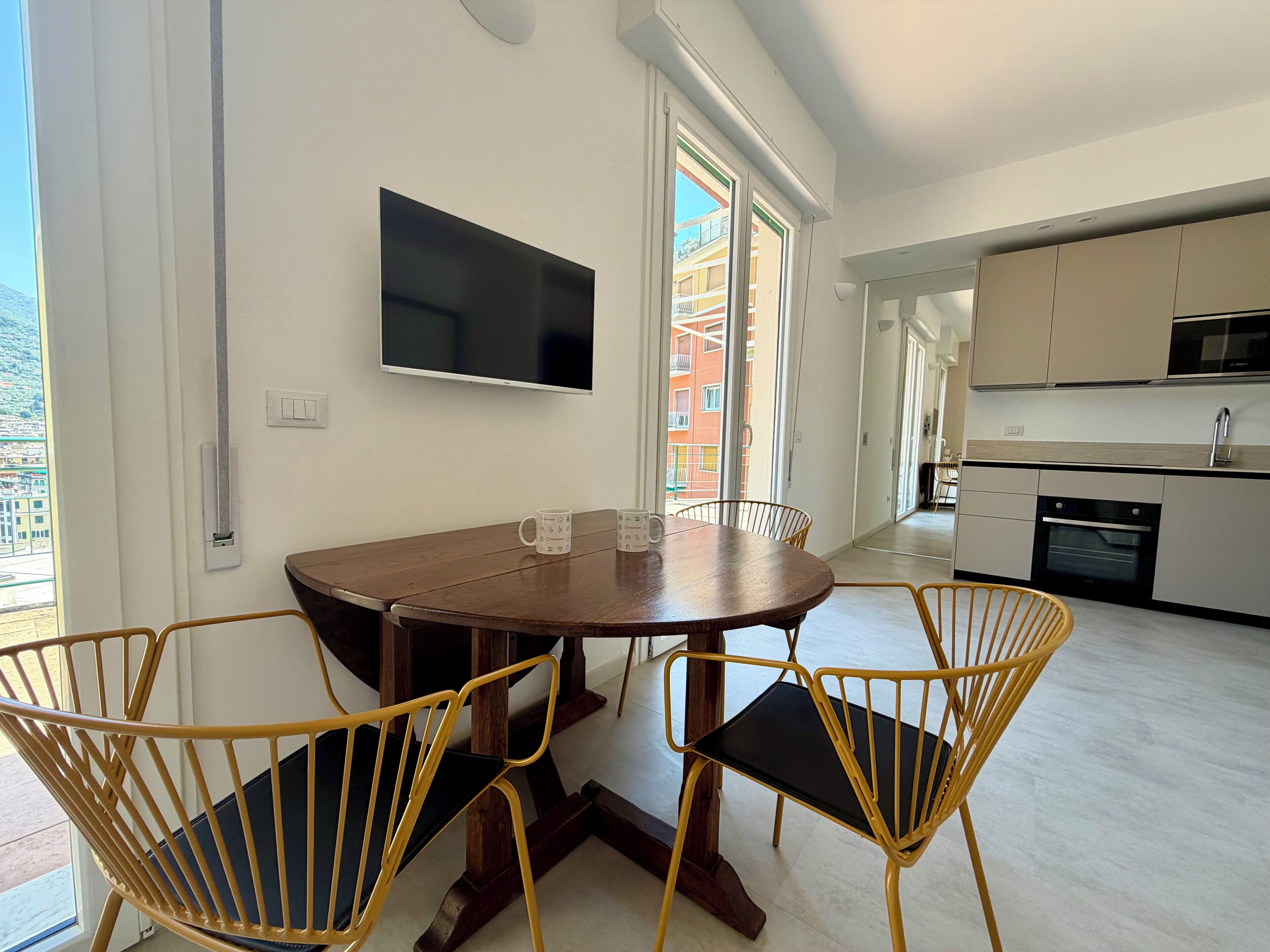 Un coin repas avec une table ronde, quatre chaises, un téléviseur à écran plat et une cuisine en arrière-plan.