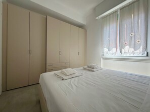A bedroom with a bed, a wardrobe, and a window with curtains. - Peonie 5 - Two Bedroom Apartment, Sleeps 5 (Rapallo)
