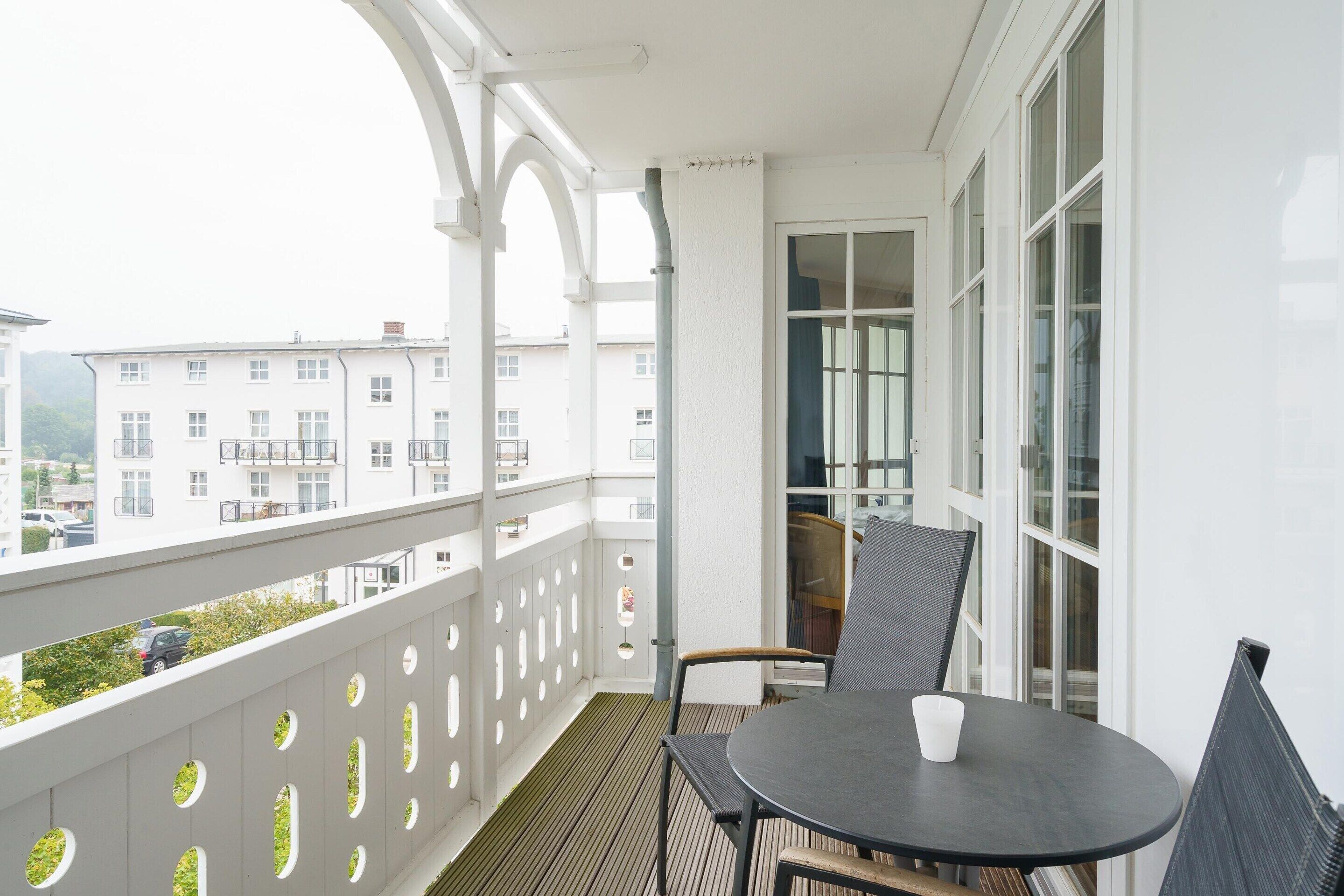 Ein Balkon mit Tisch und Stühlen und Blick auf Gebäude, mit einer weißen Brüstung.