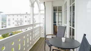 A balcony with a table and chairs, a view of buildings, and a white railing. - Moderne Ferienwohnung mit Balkon in Sellin (Sellin)