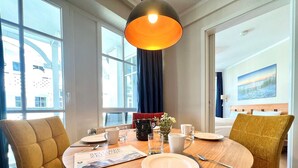A dining area with a round table, chairs, a magazine, and a vase with flowers. - Moderne Ferienwohnung mit Balkon in Sellin (Sellin)