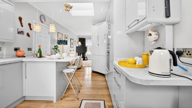 Une cuisine moderne avec des meubles blancs, un îlot central et un coin repas.