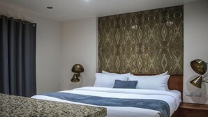 Habitación de hotel con cama, escritorio y dos lámparas de pared.
