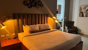 Un dormitorio moderno con una cama grande, lámparas de noche, un cabecero de diseño único y una obra de arte en la pared.