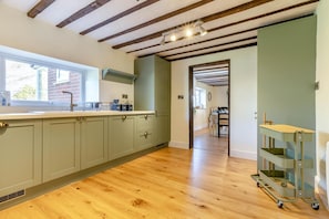 A kitchen with wooden beams, a window, and a dining area. - 4 Bed in Sharrington (oc-o37499) (Sharrington)