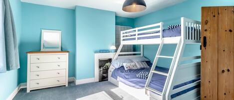 A bunk bed room with a dresser, a mirror, and a wardrobe.