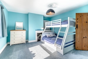 Ein Schlafzimmer mit Etagenbetten, einem Schminktischchen, einem Spiegel und einem Kleiderschrank.