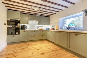 A kitchen with wooden flooring, built-in appliances, and a window with a view. - 4 Bed in Sharrington (oc-o37499) (Sharrington)