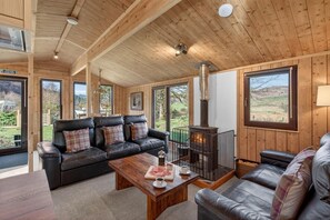 Ein gemütliches Blockhaus-Interieur mit Kamin, Ledersofas und großen Fenstern mit herrlichem Ausblick.